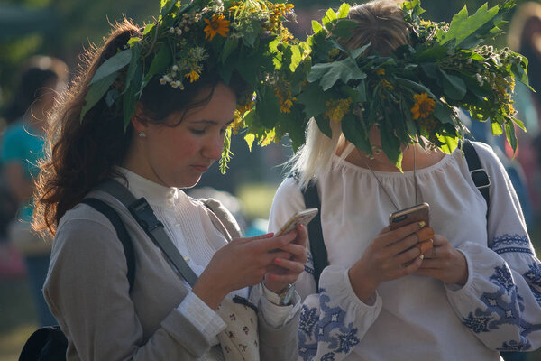 Kiev, Ukraine - July 06, 2017: Girls in wreaths from flowers with smartphones at the celebration of a traditional Slavic holiday of Ivan Kupala