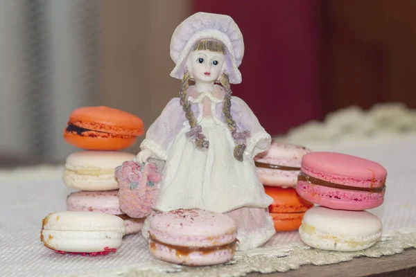 Renkli makarna kekleri ve masada retro tarzı bir kız heykeli. — Stok fotoğraf