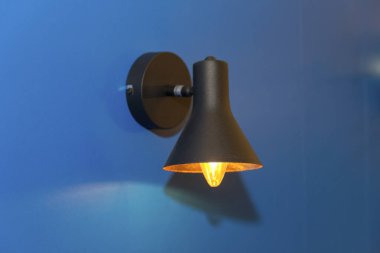 Wall lamp in retro style on the blue wall. Interior