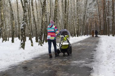 Bebek arabası kış Park ile yürüyen kadın. İnsanlar