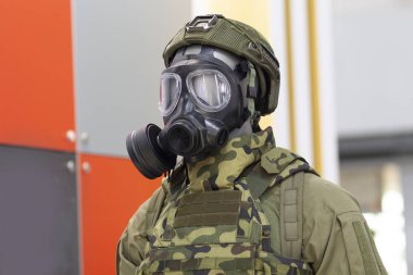 Gaz maskeli manken kafası ve yeşil işaretli özel kumaştan yapılmış kimyasal koruyucu giysi.