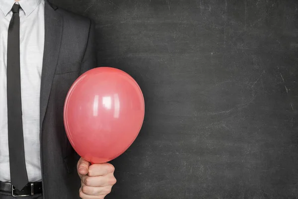 Empresario sosteniendo globo rojo contra pizarra en blanco — Foto de Stock