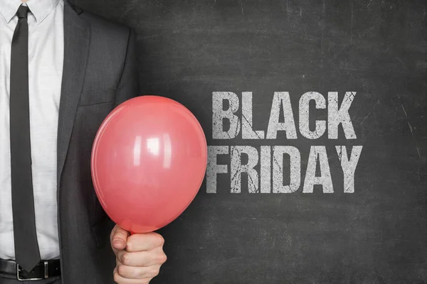 Empresario sosteniendo globo con texto de Viernes Negro en pizarra —  Fotos de Stock
