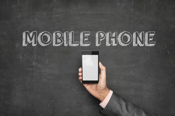 Бізнесмен тримає мобільний телефон під текстом на дошці — стокове фото