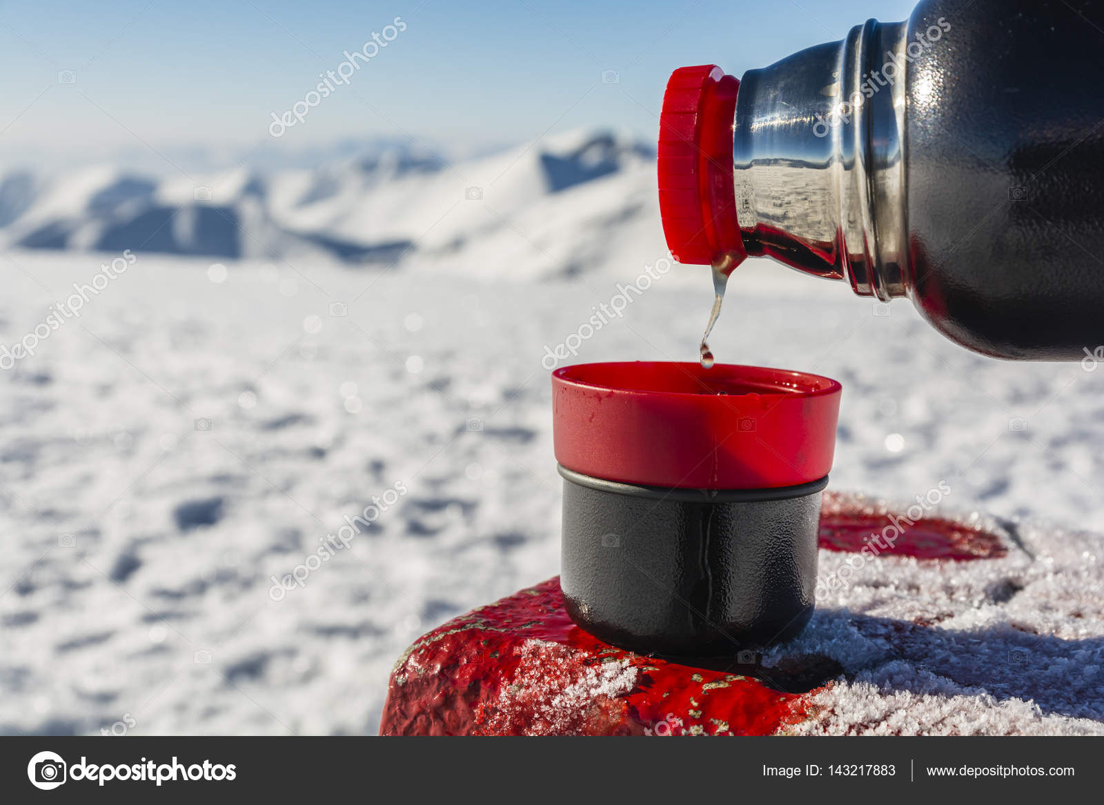 Pouring hot tea from a thermos into a cup in the mountains. Stock