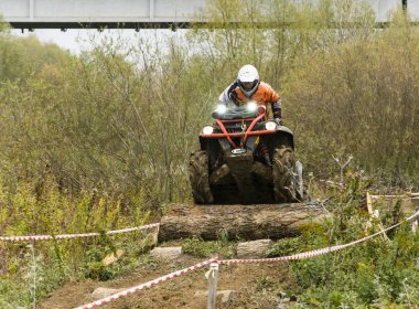 Man riding a quad meets an obstacle in the form of a tree trunk. clipart