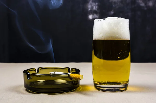 Fumo di sigaretta sul posacenere e boccale di birra . — Foto Stock