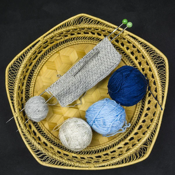 Tre olika färgade bollar av ull och början av Trikåplagg i korgen. — Stockfoto