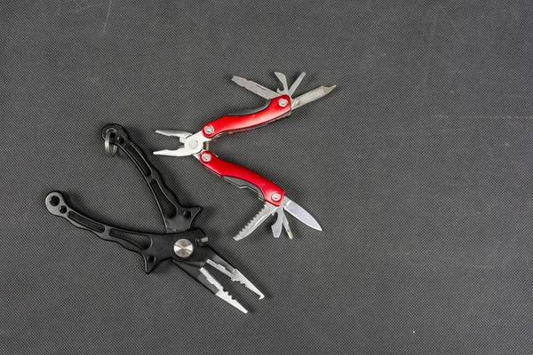 Black pliers and red folding multifunctional tool for anglers. — Stock Photo, Image