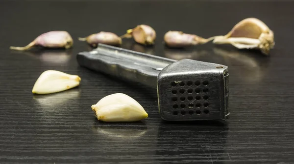 Peeled garlic clove and garlic press.