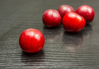 Olgun kırmızı Erik, bir grup ahşap bir masa üzerinde birkaç Erik.