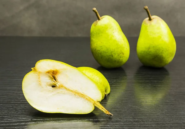 Cut half a pear on a wooden dark table.