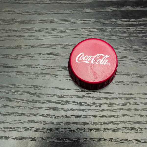 Rode pet met een fles van Coca-Cola op een donkere houten tafel. — Stockfoto