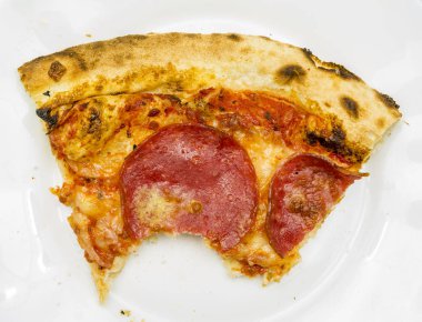 Pizza beyaz tabakta ısırıldı bir kısmını closeup.