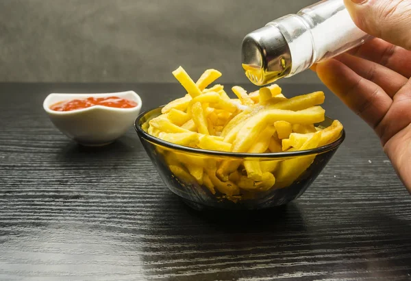 Salting French fries in a bowl. — Stock Photo, Image