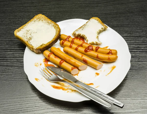 Tallrik med korv, ketchup och skivor med smör till frukost. — Stockfoto