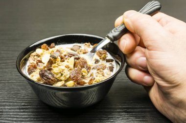 Hızlı sağlıklı kahvaltı. Fıstık, sütlü çikolata, karamel ve süt ile kuru üzüm ile gevrek kavrulmuş kakao müsli ile kase.