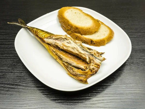 Um prato branco de cavala defumada com fatias de pão preparadas para comer . — Fotografia de Stock