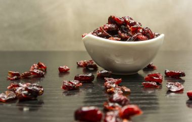 Kurutulmuş cranberries bir kase ve masanın üzerine dağılmış.
