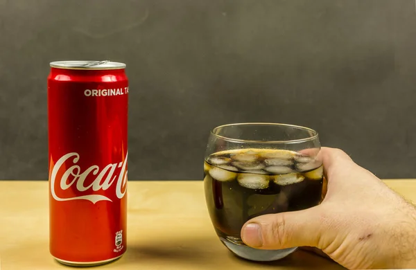 Ein Glas Coca-Cola mit Eiswürfeln in der Hand. — Stockfoto