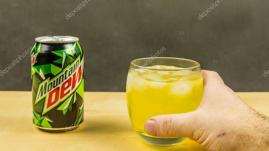 Niedomice, Poland - March 09, 2018: A glass of Mountain Dew with ice cubes held in hand.