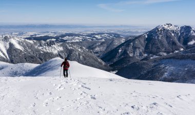 Dağlık trek geniş bir sırt ile karda. Uzun yürüyüşe çıkan kimse, karla kaplı dağ sırtı azalan hayran aşağılarda ve çevreleyen dağ zirveleri.