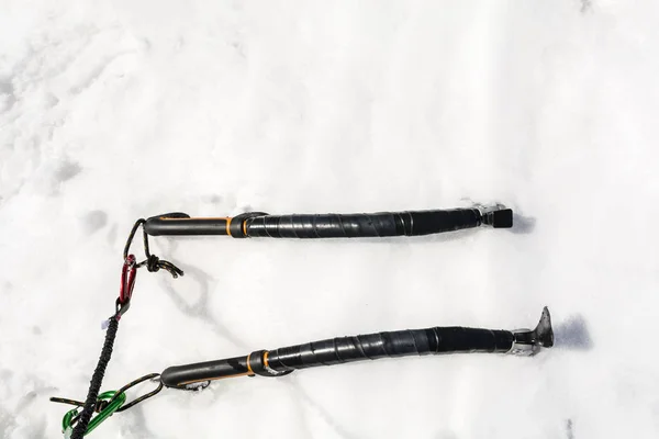 Zwei Eispickel zum Klettern mit Karabiner und Schlüsselbändern, die in den Schnee getrieben werden. — Stockfoto