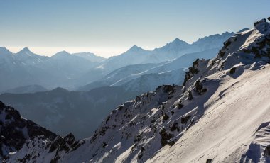 Karlı manzaradaki tepeler arasındaki vadilerde sabah sisleri. Peri masalı atmosferi bir dağ manzarası yaratıyor..