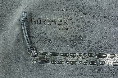 Niedomice, Poland - May 06, 2019: Water drops on the material with Gore-Tex Pro waterproof membrane and YKK zip. clipart