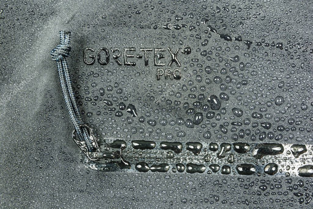 Niedomice, Poland - May 06, 2019: Water drops on the material with Gore-Tex Pro waterproof membrane and YKK zip.