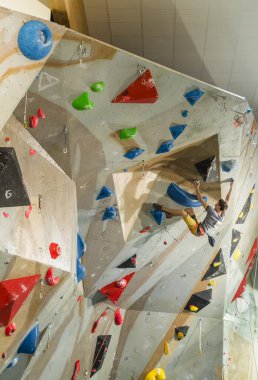 Tarnow, Polonya - 28 Temmuz 2019: Tırmanma duvarına tırmanan tırmanıcı. Yolun sonundaki sarkık ve zor bir yerde dövüş..