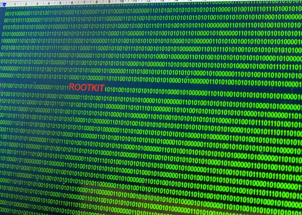 Red inscription Rootkit in malicious computer code written by a hacker. Picture of a computer screen with a dangerous program code.