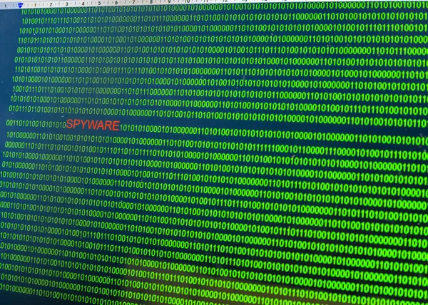 Red inscription Spyware in malicious computer code written by a hacker. Picture of a computer screen with a dangerous program code.