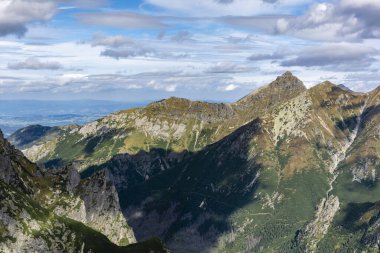 Sonbahar çimenlerindeki dağ zirvelerinin güzel manzarası mavi gökyüzündeki bulutlar.