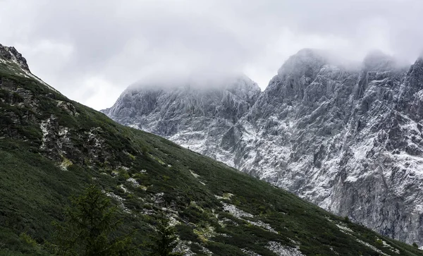 Frosted and snowy walls of the peaks. Tops in covered with clouds.