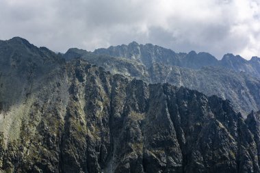 Dağlarda bulutlu bir gün. Kara bulutların üzerinde sallanan kayalık dağ sırtları.