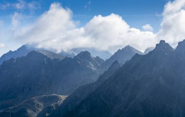 Dağ manzarası. Tepeler ve bulutlar arasından sabah ışıkları geçiyor..