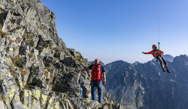 Tatranska Polianka, Slovakya - 01 Eylül 2019: Kurtarıcı (Horska, HZS) helikopterden dağ geçidine inen bir iple Gerlach üzerinde bir rehberle yürüyen yaralı bir turiste.