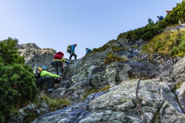 Tatranska Lomnica, Slovakya - 14 Eylül 2019: Bir grup turist dağlardaki kayalık bir yola tırmanıyor ve bu yolda zincirler de var..