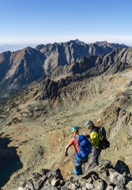 Strbske Pleso, Slovakya - 25 Ekim 2019: Bir çift dağcı zirveden inmeye başladı. Adam, ortağını bağlamak için ipi hazırlıyor..
