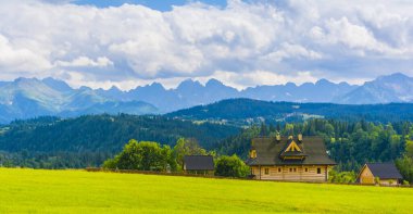Czarna Gora, Polonya - 09 Temmuz 2019: Podhale 'de turistler için kiralanan güzel geleneksel ahşap binalar. Arka planda dağlar olan manzara (Tatry Dağları).