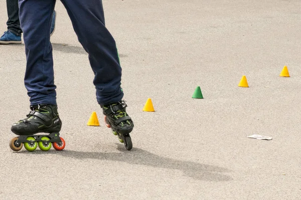 Patineur à roulettes pratiquant le slalom le long d'une ligne de cônes sur asphalte — Photo