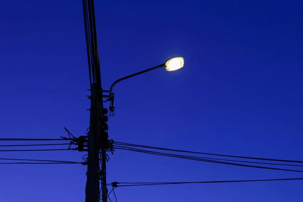 El post och kabel linje med gatlykta på natten — Stockfoto