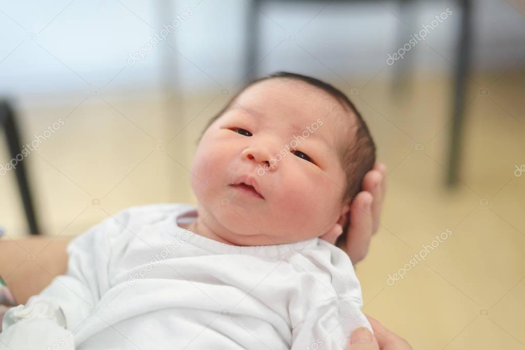 two day old asian baby boy in the comfort of moms arms, newborn