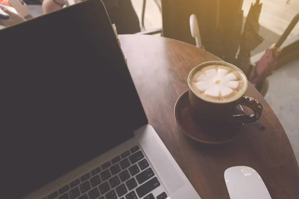 Koffiekopje en laptop op houten tafel in de coffeeshop. bedrijven c — Stockfoto