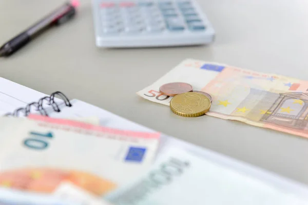 Notas e moedas de euro contando com calculadora, caderno e caneta na mesa — Fotografia de Stock