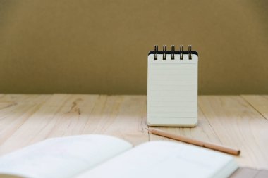 Küçük not kitap kağıdı (Not Defteri) ayakta bilgi ile kalem ve ahşap masa kitap yazmak için
