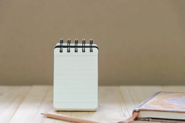 Papier pour carnet de notes (bloc-notes) pour écrire des informations avec crayon et livre sur table en bois — Photo