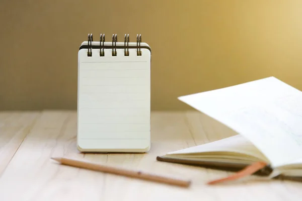 Papier pour carnet de notes (bloc-notes) pour écrire des informations avec crayon et livre sur table en bois — Photo