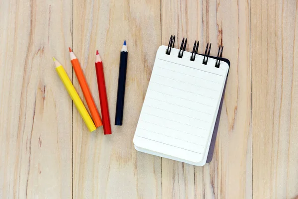 Papier carnet de notes (bloc-notes) pour écrire des informations avec crayon de couleur sur une table en bois. vue d'en haut — Photo